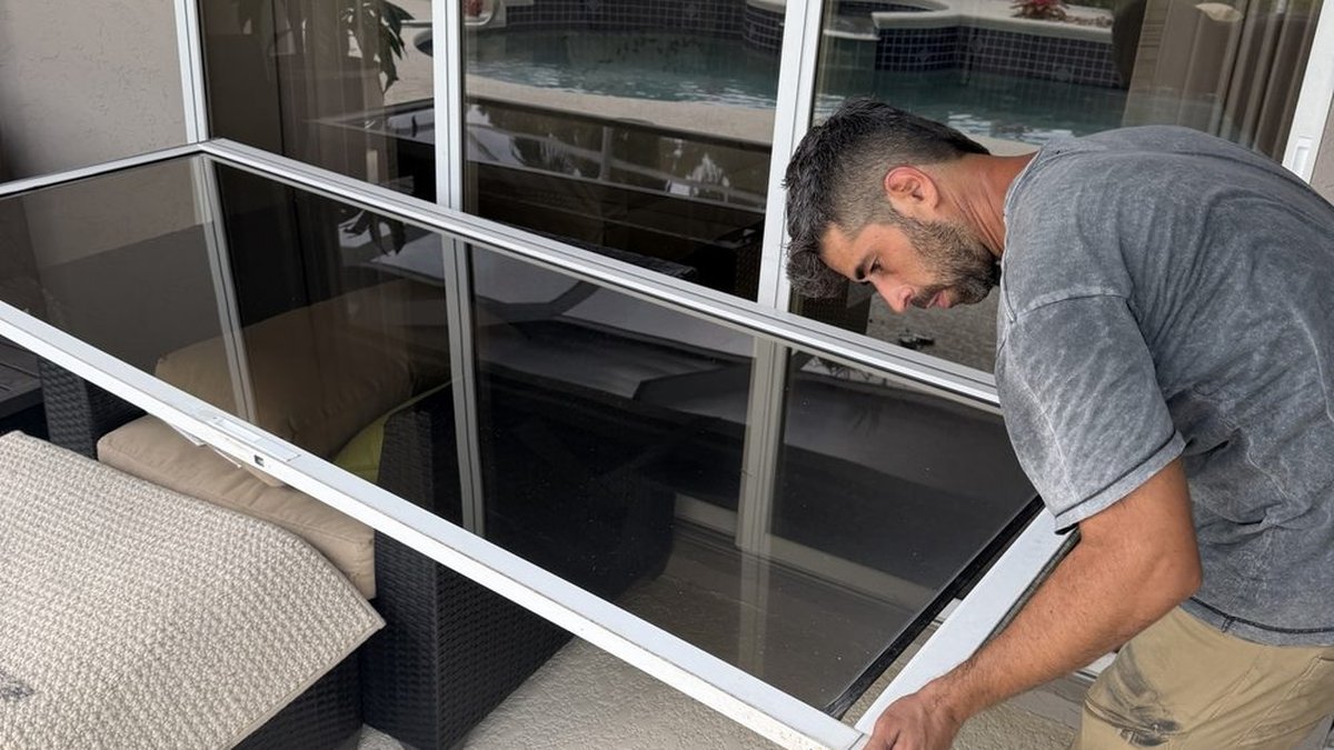 Technician replacing a sliding glass door roller on a South Florida patio